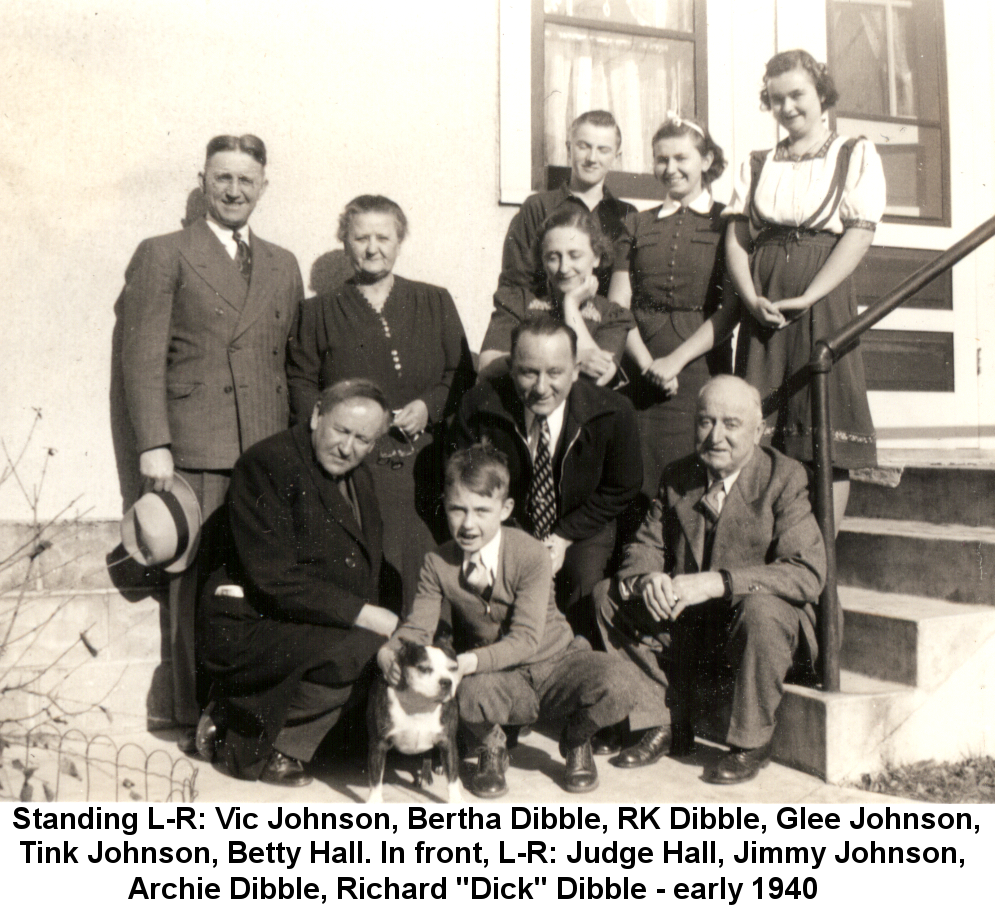 Black and white photo of a family group on the back steps of a white stucco house in early 1940. Standing: Vic Johnson, Bertha Dibble, Glee Johnson, Richard Kenneth Dibble, Tink Johnson, Betty Hall. In front, squatting: Judge Charles P. Hall, Jimmy J. Johnson with a small black and white dog, Archie Dibble, Richard 'Dick' Dibble.